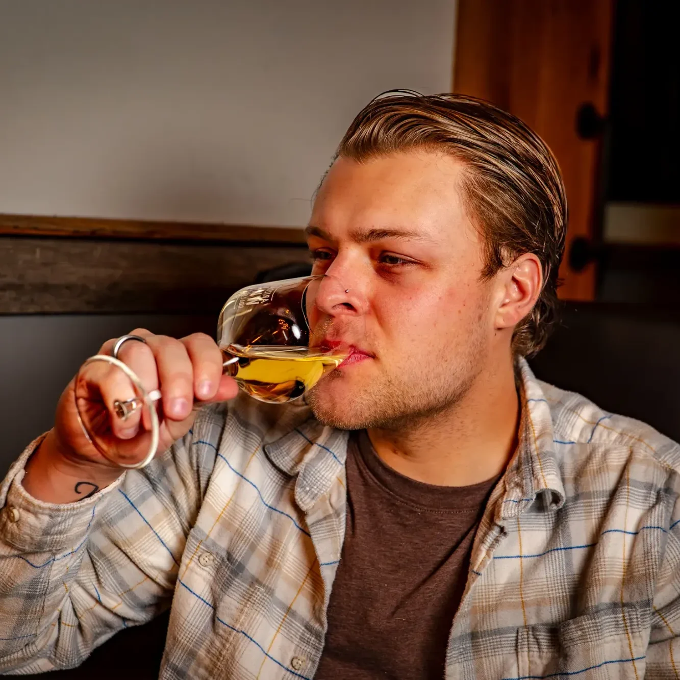 Young man with a nose ring drinking a glass of Jumping Cholla White wine